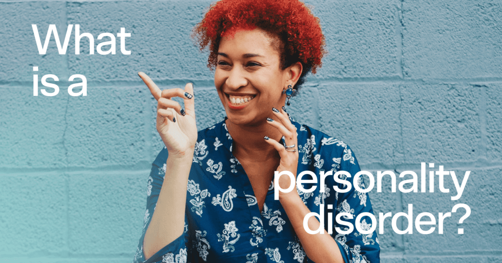 Woman stands in the middle of the screen pointing with her right hand. She is looking to the right and laughing with her teeth. She is wearing a dark blue shirt and standing in front of a light blue wall. Text is on top of the image that reads what is a personality disorder in white font.
