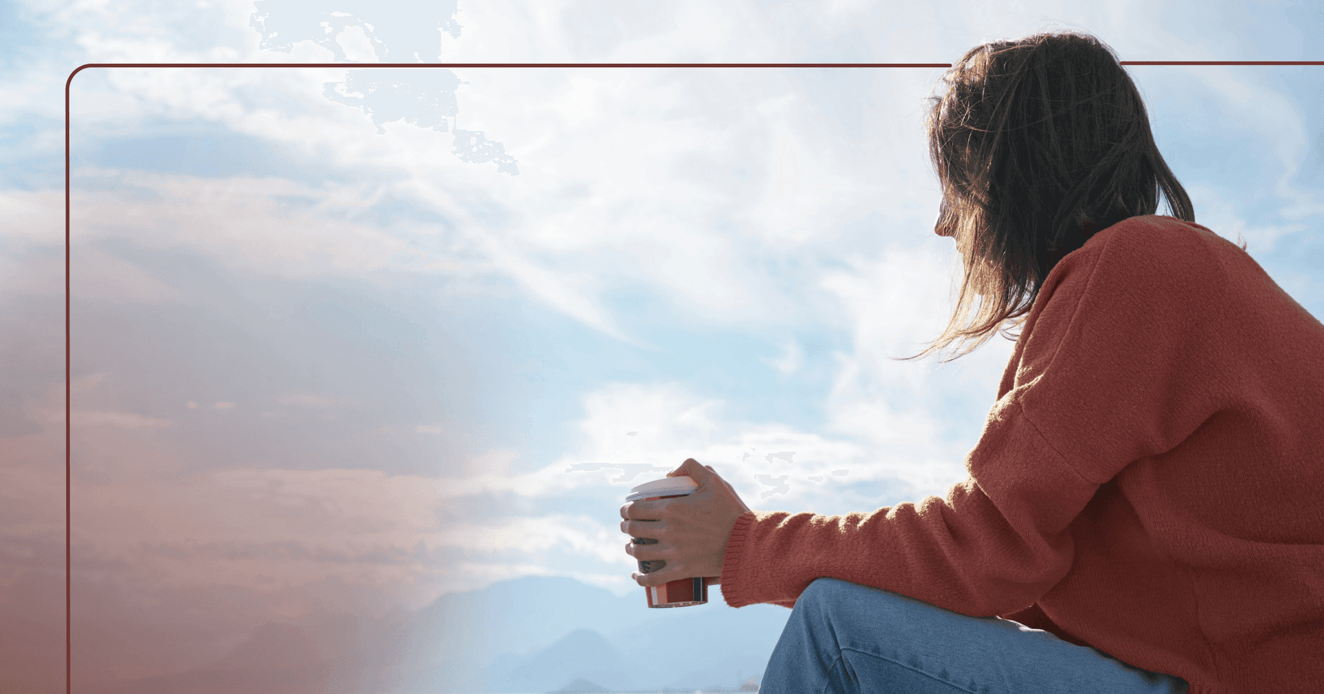 A woman in an orange sweater sits with her hands on her knees and looks out into a visible partly cloudy sky. She is holding a takeout coffee cup.